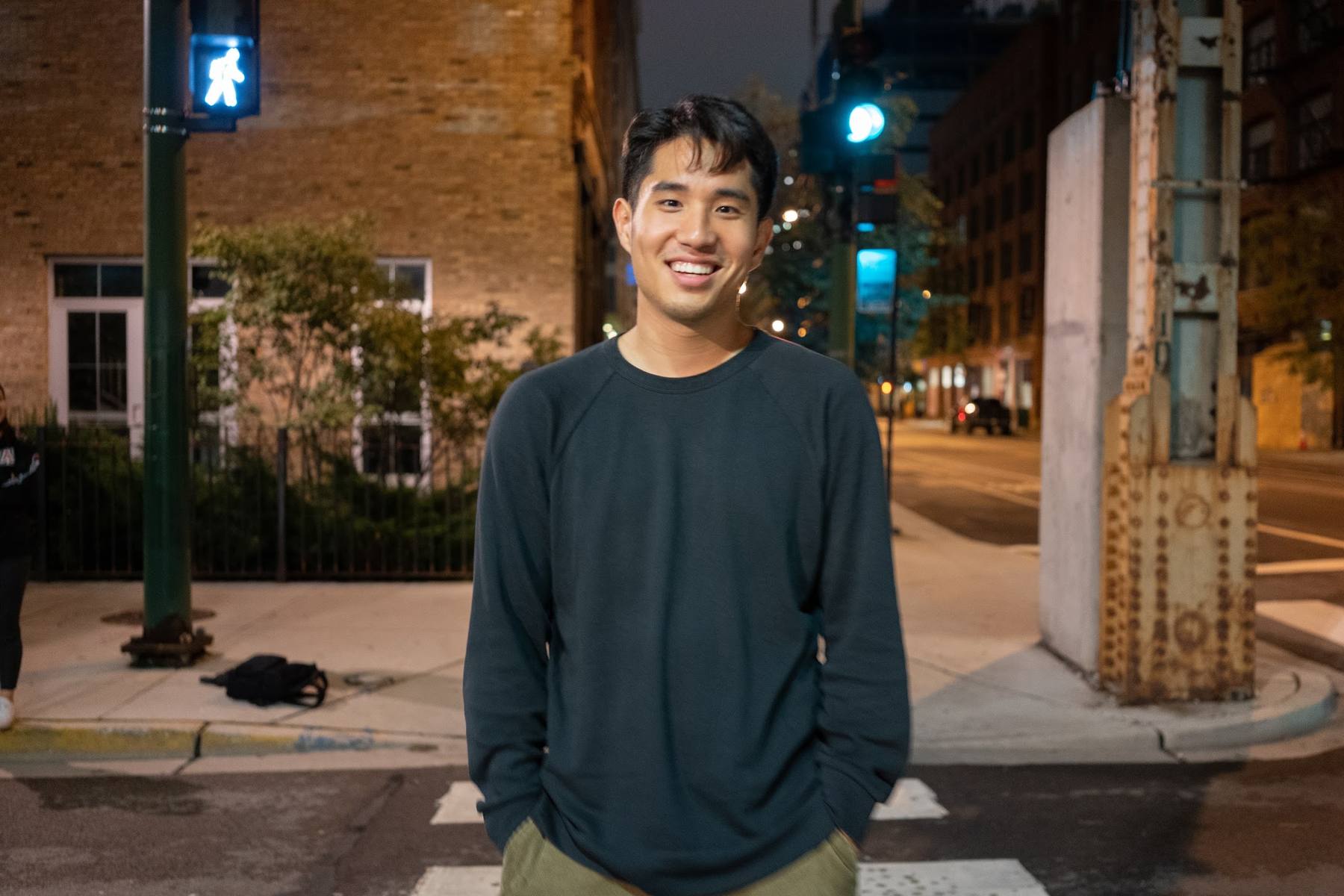 Bryan Jun smiling on a city street corner at night